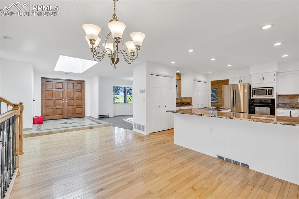 Image 18 of 46: Kitchen featuring light wood-type flooring, a skylight, dark stone countert