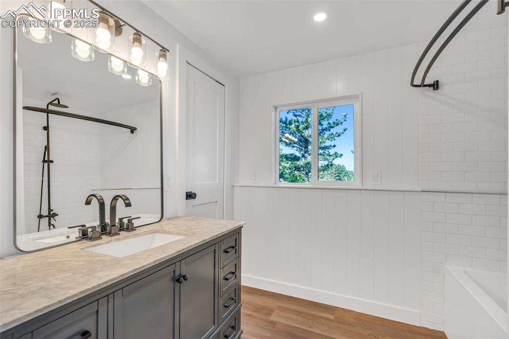 Image 21 of 46: Bathroom featuring vanity, a tub, wood finished floors, and a shower
