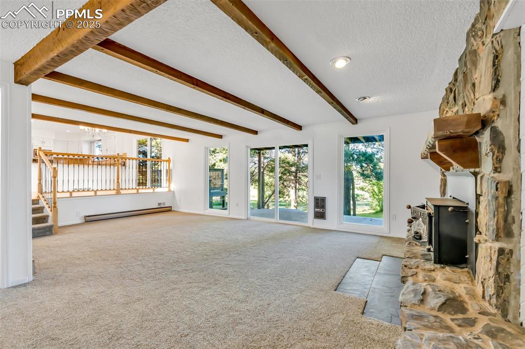 Image 27 of 46: Unfurnished living room with a textured ceiling, carpet, stairs, beam ceili