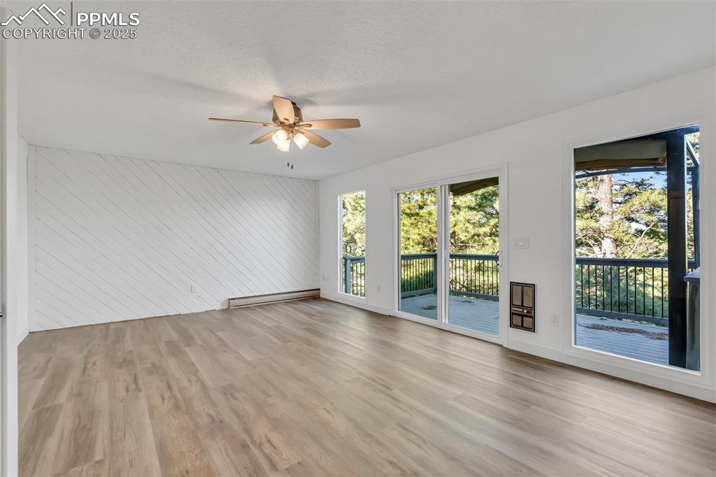 Image 29 of 46: Empty room with ceiling fan, light wood-type flooring, wood walls, baseboar