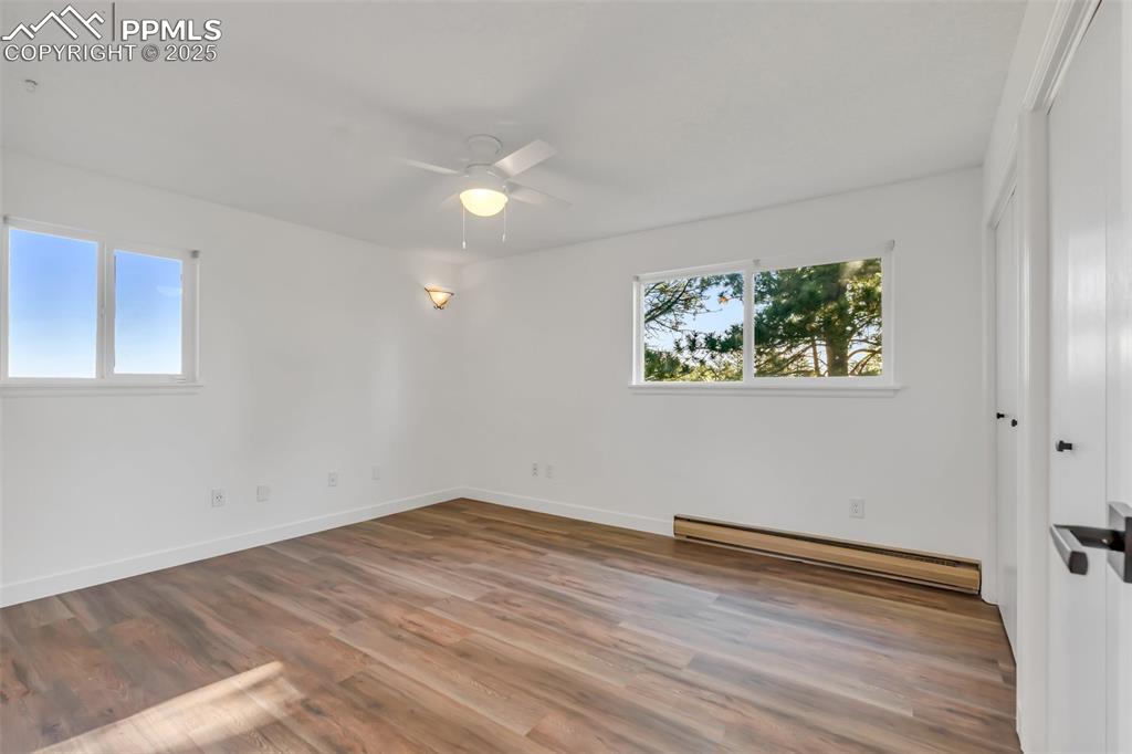 Image 34 of 46: Unfurnished bedroom with a baseboard heating unit, wood finished floors, a