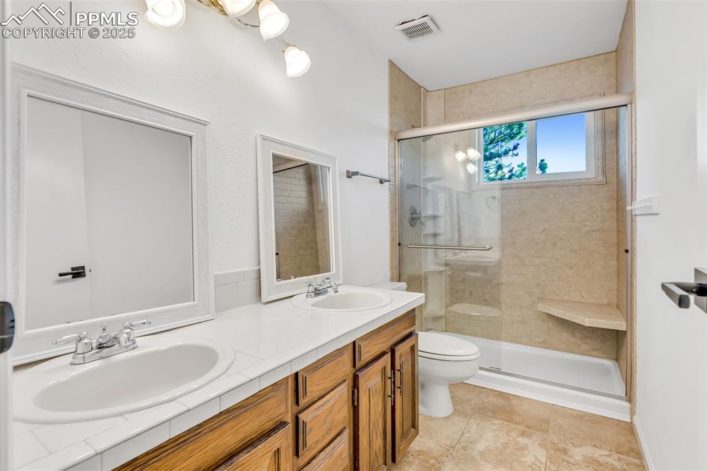 Image 36 of 46: Full bathroom with a shower stall and double vanity