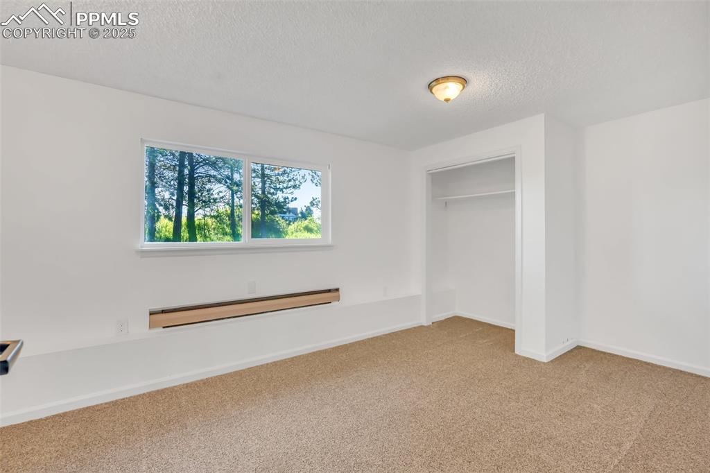 Image 37 of 46: Unfurnished bedroom featuring carpet flooring, baseboard heating, and a tex