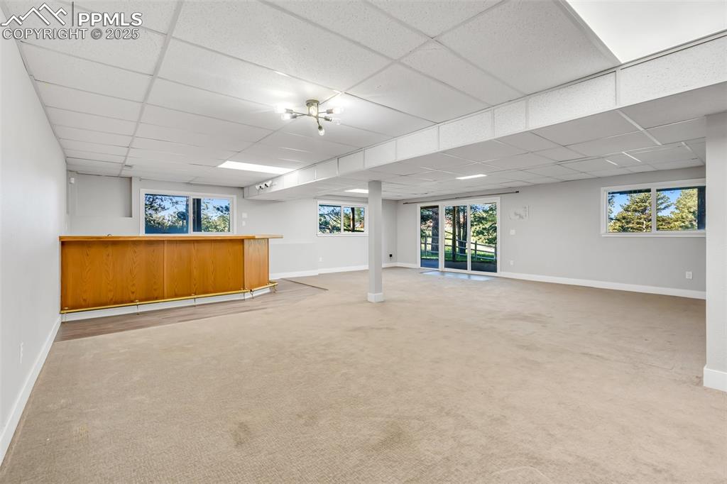 Image 38 of 46: Below grade area featuring bar area, a drop ceiling, and carpet flooring