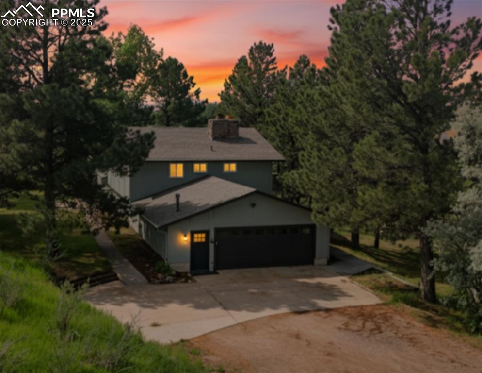 Image 40 of 46: View of front of house with driveway, a chimney, and a garage