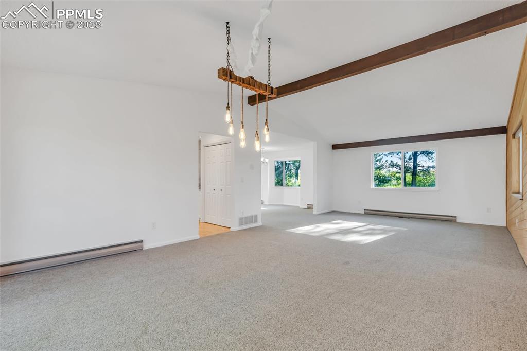 Image 6 of 46: Unfurnished living room with carpet floors, beamed ceiling, baseboard heati