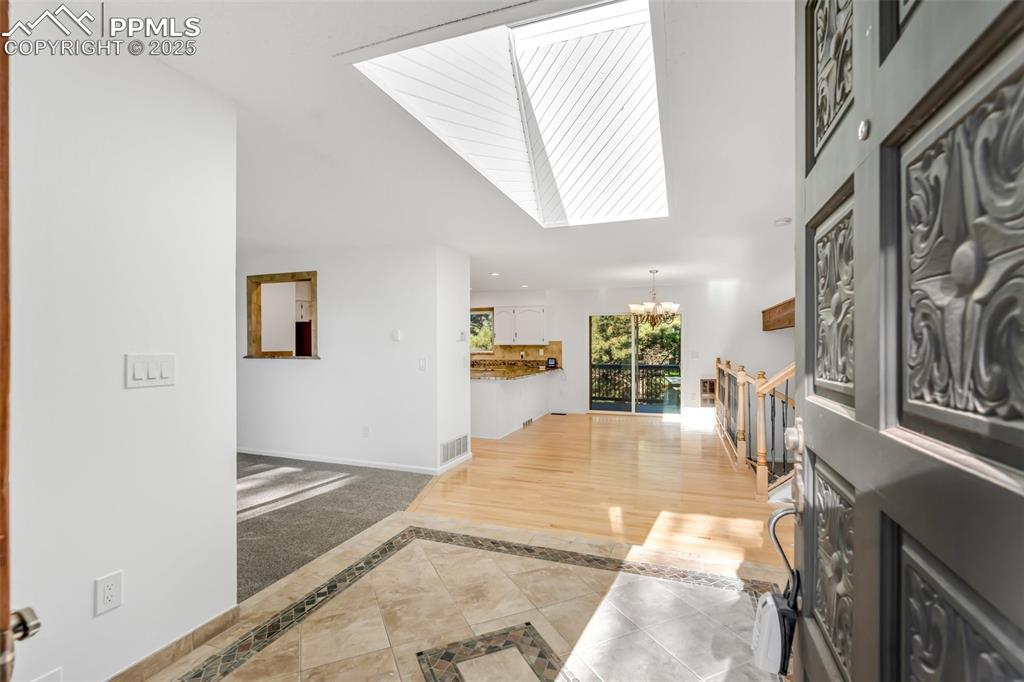 Image 7 of 46: Foyer entrance featuring a chandelier, a skylight, and inlaid floor details