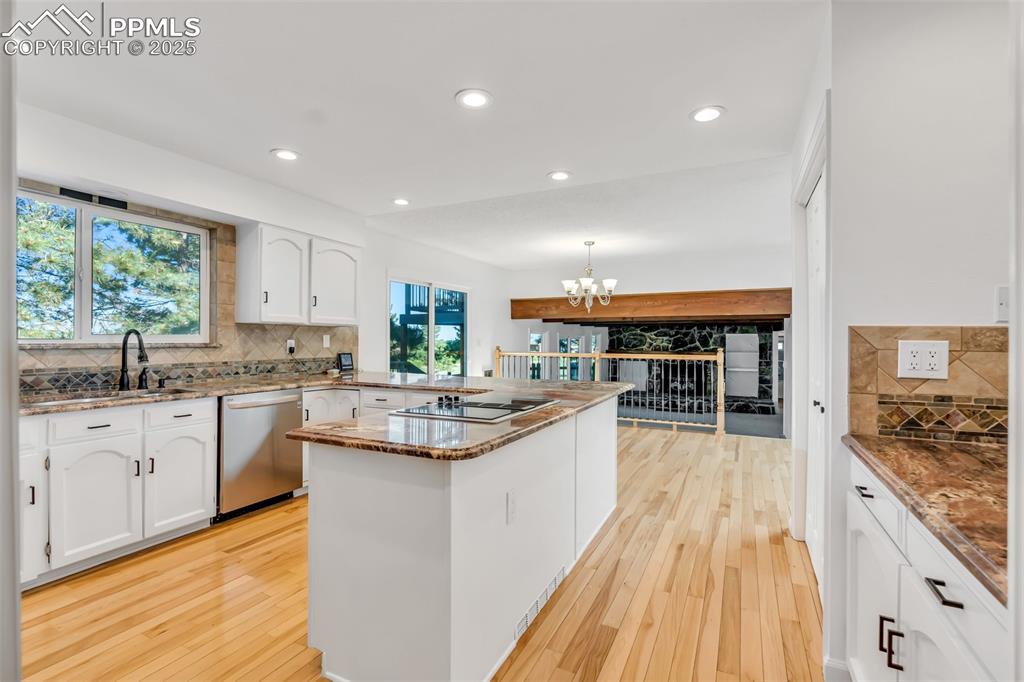 Image 8 of 46: Kitchen with a peninsula, tasteful backsplash, white cabinetry, light wood