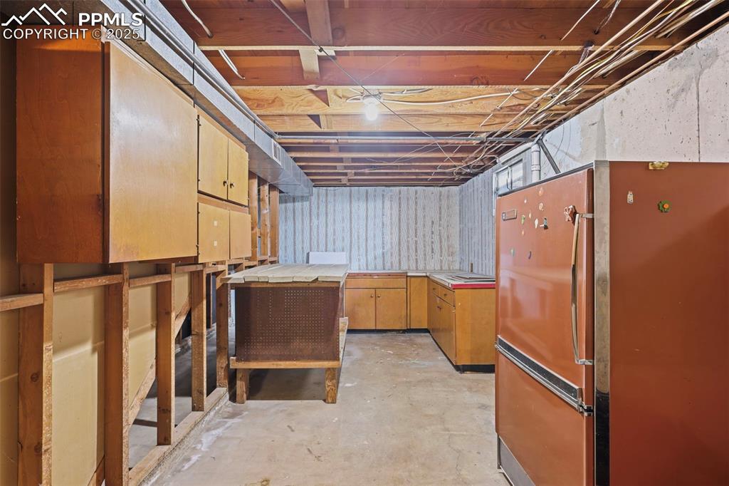 Image 25 of 35: Unfinished basement with freestanding refrigerator