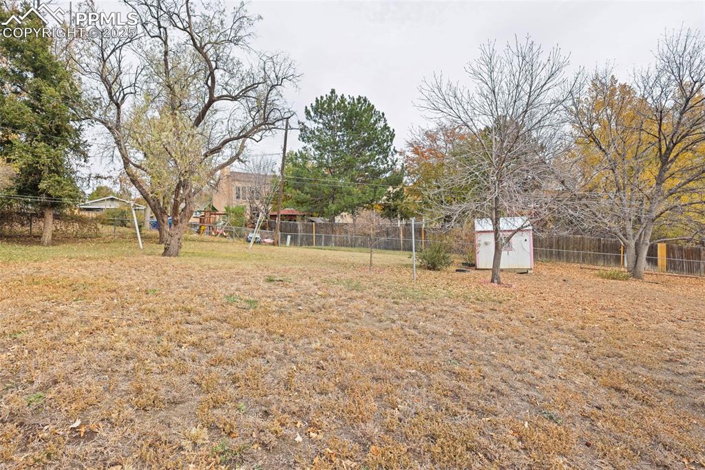 Image 28 of 35: Fenced backyard featuring a storage unit