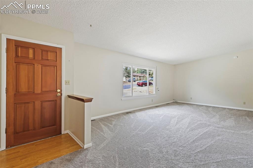 Image 5 of 35: Carpeted entryway featuring a textured ceiling and baseboards