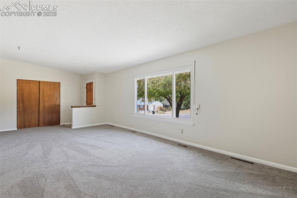 Image 6 of 35: Unfurnished room with carpet and a textured ceiling