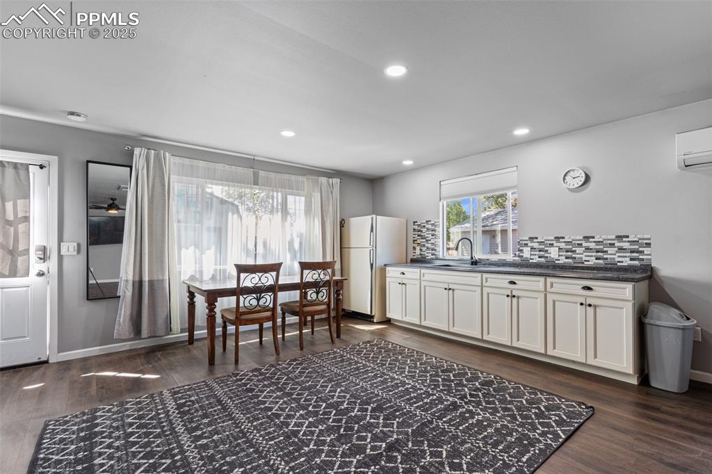 Image 26 of 36: Kitchen with tasteful backsplash, dark wood-style floors, freestanding refr