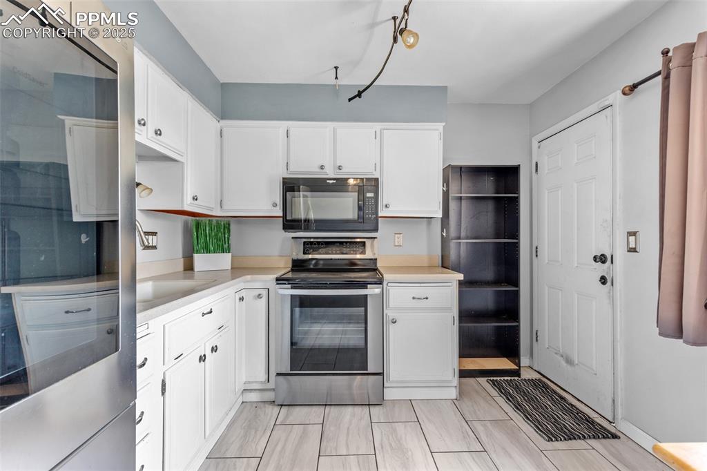 Image 8 of 36: Kitchen with appliances with stainless steel finishes, light countertops, a