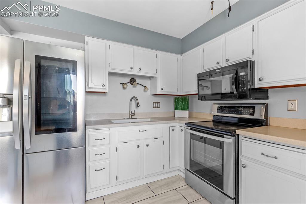 Image 9 of 36: Kitchen featuring stainless steel appliances, light countertops, white cabi
