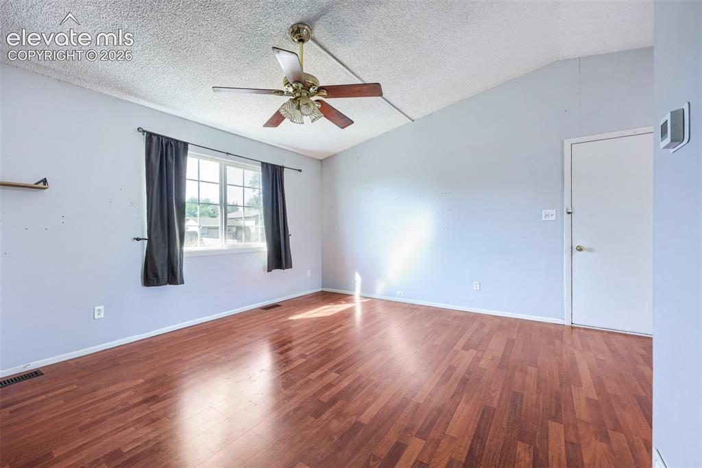 Image 10 of 38: Spacious room featuring wood-finish flooring, vaulted ceiling, and a ceilin