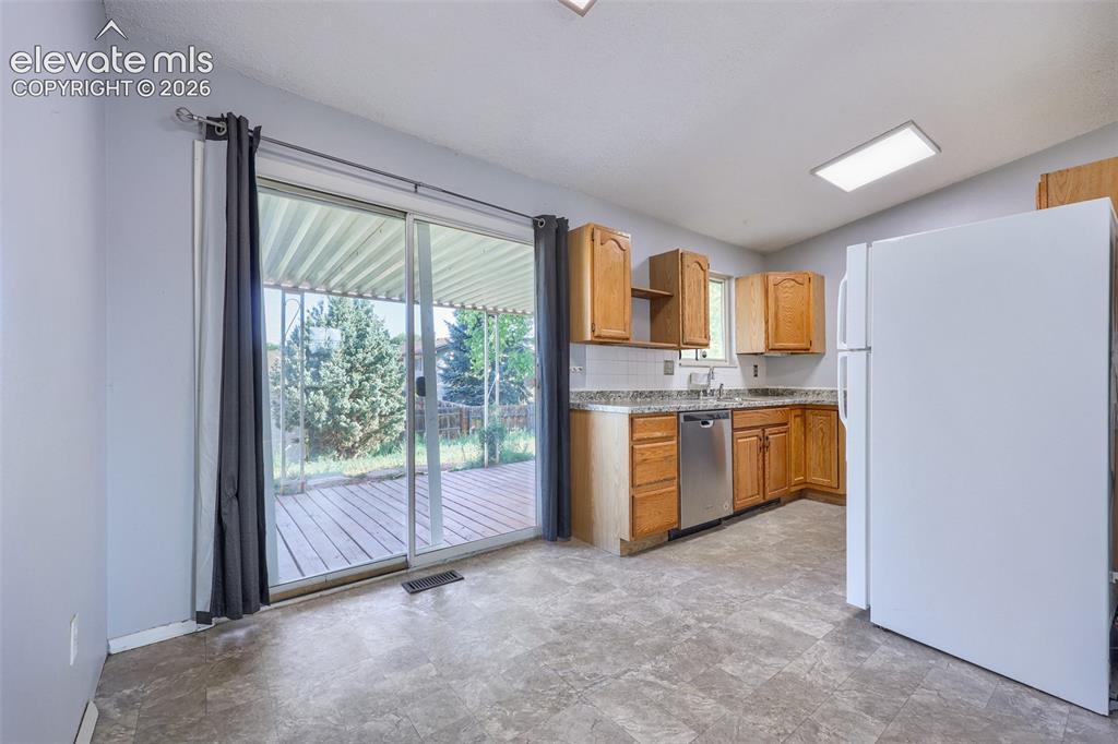 Image 11 of 38: Kitchen featuring wood cabinetry, stainless steel dishwasher, and a white t