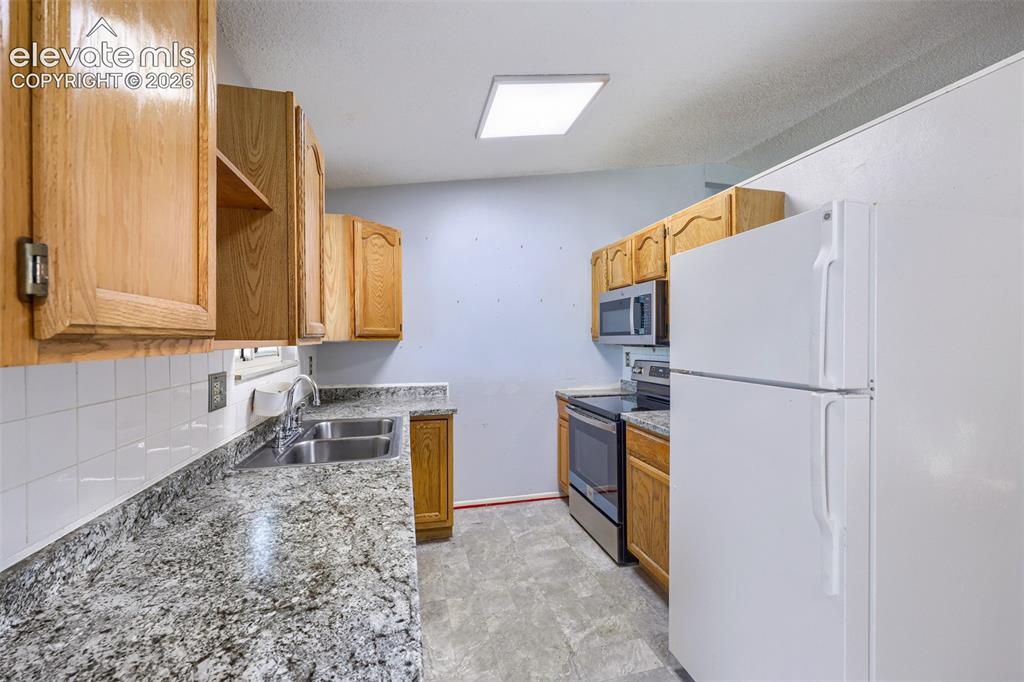 Image 13 of 38: Kitchen featuring granite countertops, wood cabinetry, a double basin stain