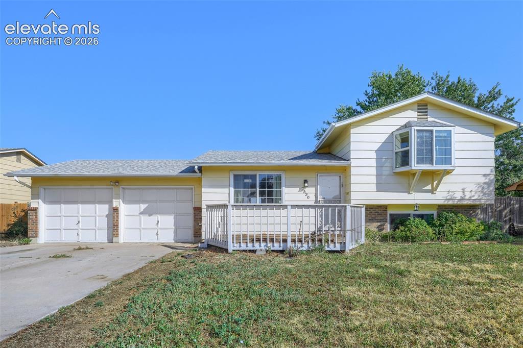Image 2 of 38: Split-level residence featuring light-colored siding and a multi-car garage
