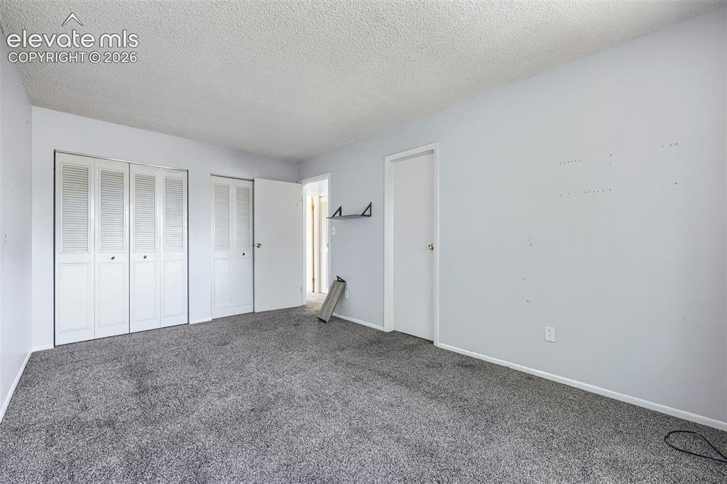 Image 22 of 38: Expansive room featuring plush gray carpeting, textured white ceiling, ligh