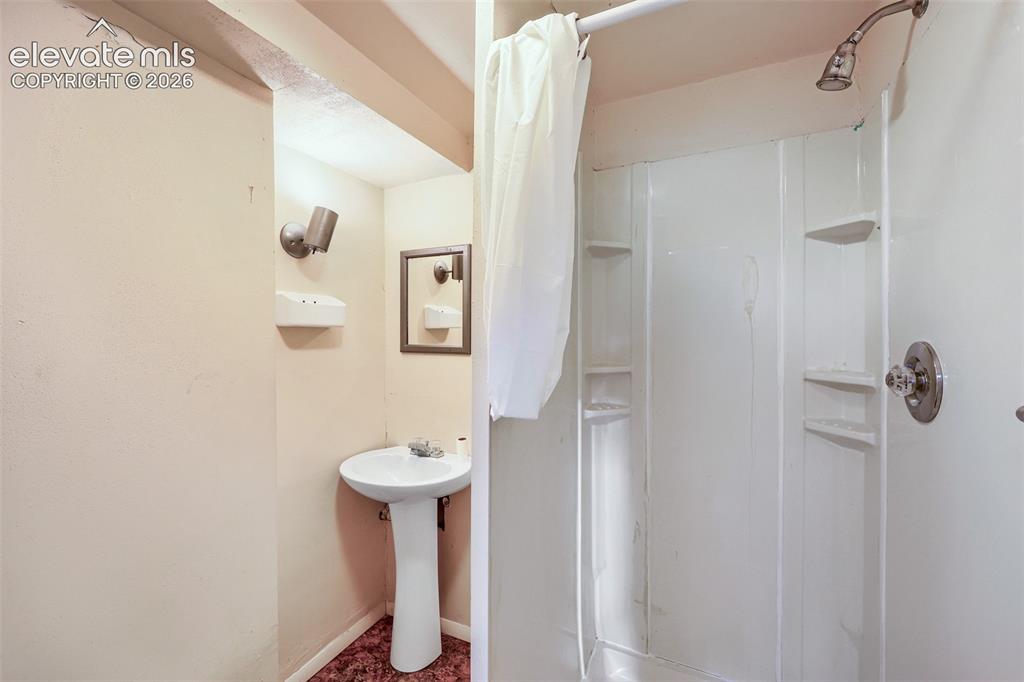Image 29 of 38: Compact bathroom featuring a white pedestal sink, wall-mounted lighting, an