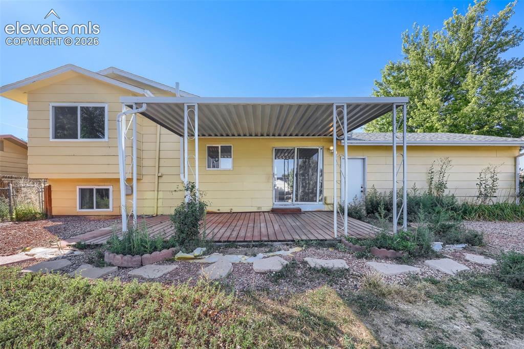 Image 31 of 38: Rear exterior featuring a covered wood-finish deck, sliding glass door acce