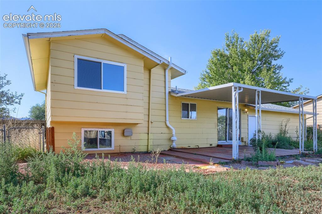 Image 32 of 38: Rear exterior featuring yellow siding, a ground-level window, an upper-leve