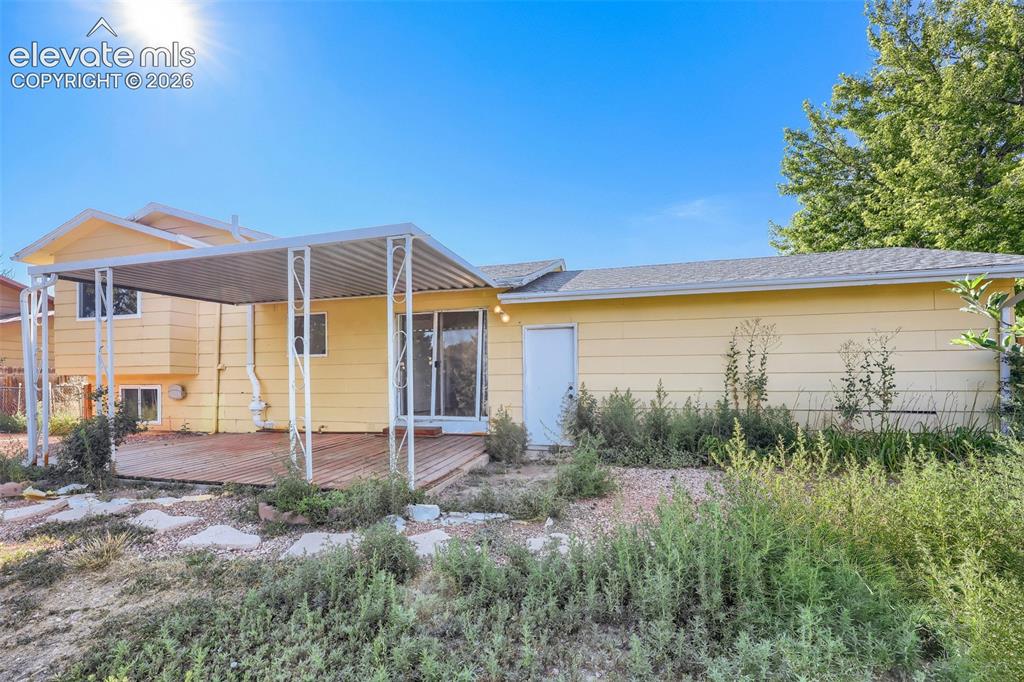 Image 33 of 38: Rear exterior with a covered patio area featuring a slatted roof and decora