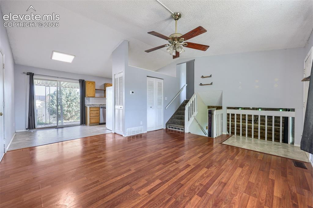 Image 6 of 38: Spacious living area featuring wood-finish flooring, a ceiling fan, and a n