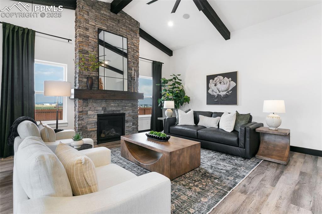 Image 10 of 22: Living room featuring wood finished floors, high vaulted ceiling, a stone f