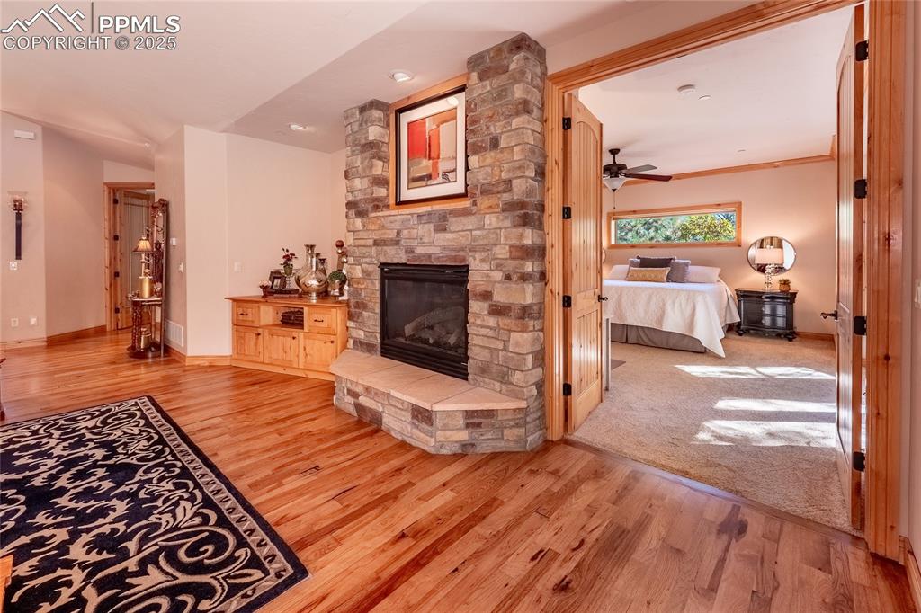 Image 10 of 47: Living room featuring a stone fireplace, light wood-type flooring, and a ce