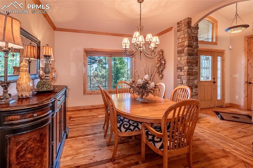 Image 11 of 47: Dining area featuring crown molding, light wood-style flooring, and a chand