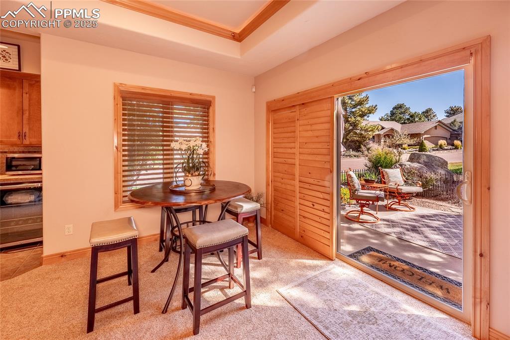 Image 15 of 47: Dining area with light carpet, ornamental molding, and a raised ceiling