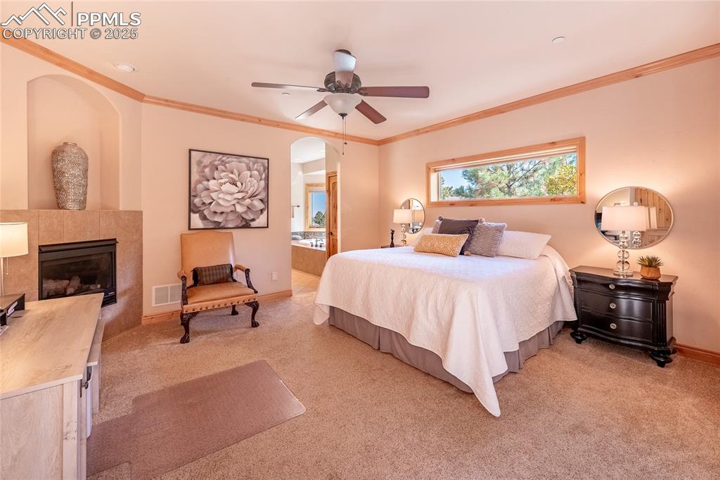 Image 17 of 47: Bedroom with ensuite bath, a fireplace, ornamental molding, light colored c