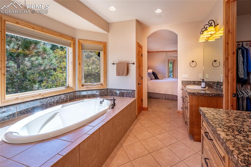 Image 19 of 47: Bathroom with vanity, a garden tub, light tile patterned floors, connected