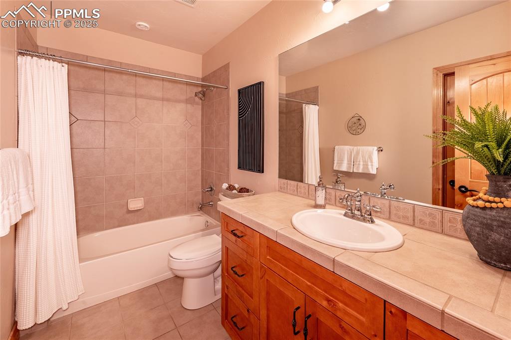 Image 28 of 47: Bathroom with shower / bath combo with shower curtain, light tile patterned