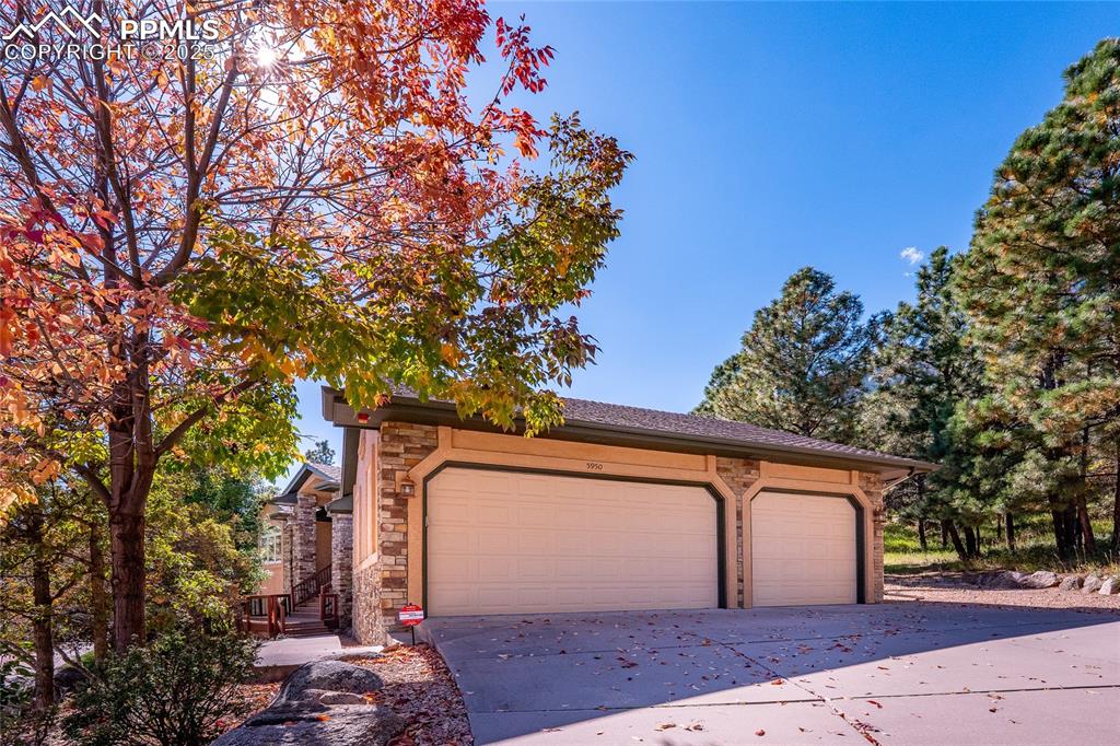 Image 40 of 47: View of garage side of property with stone siding and concrete driveway