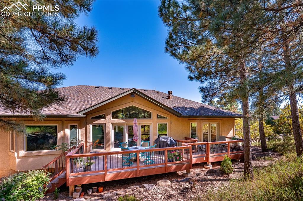Image 41 of 47: Back of property featuring roof with shingles, a wooden deck, and stucco si