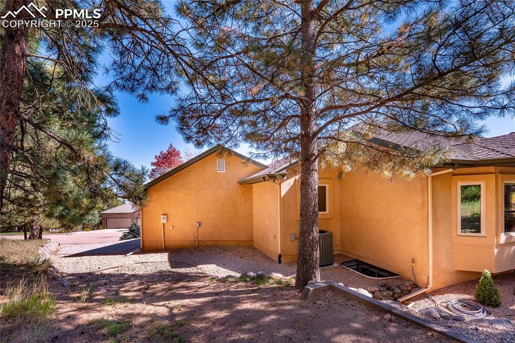 Image 45 of 47: View of side of home with stucco siding and a central AC unit
