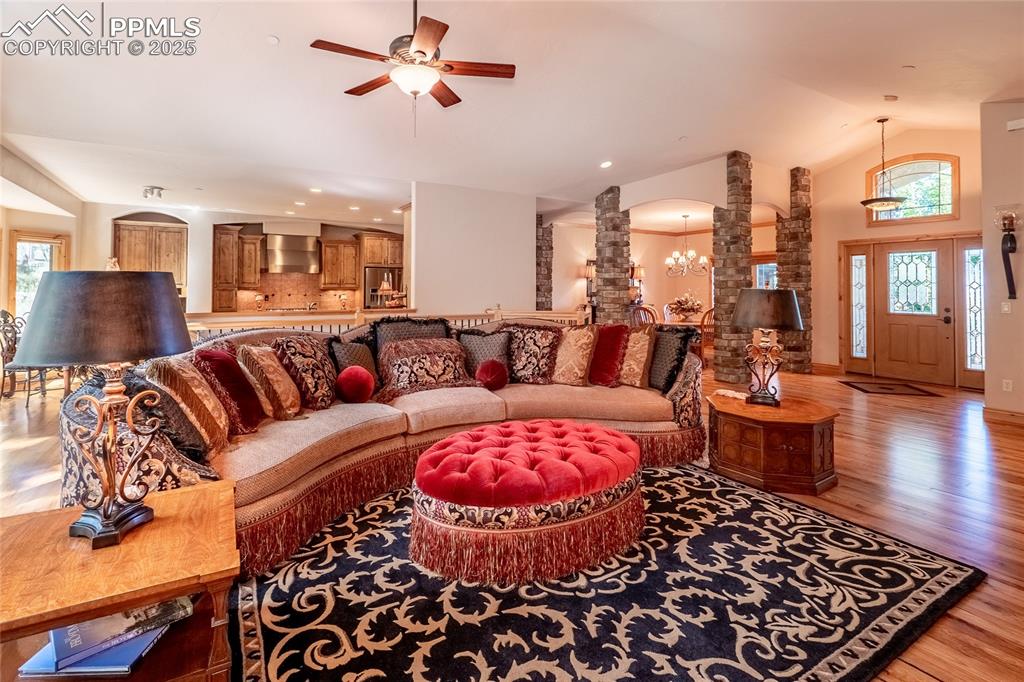 Image 7 of 47: Living room featuring arched walkways, light wood-style flooring, a chandel
