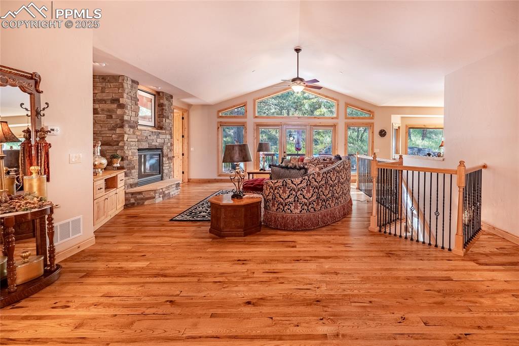 Image 9 of 47: Living room with a large fireplace, lofted ceiling, light wood finished flo