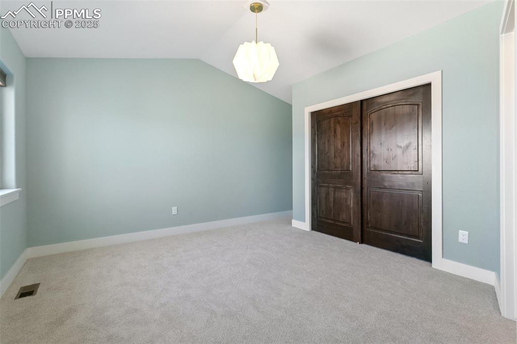 Image 28 of 49: Unfurnished bedroom featuring carpet floors, visible vents, lofted ceiling,