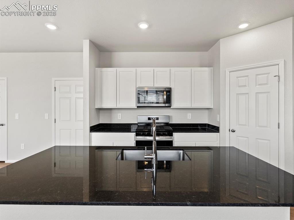 Image 2 of 23: Kitchen featuring dark stone countertops, appliances with stainless steel f