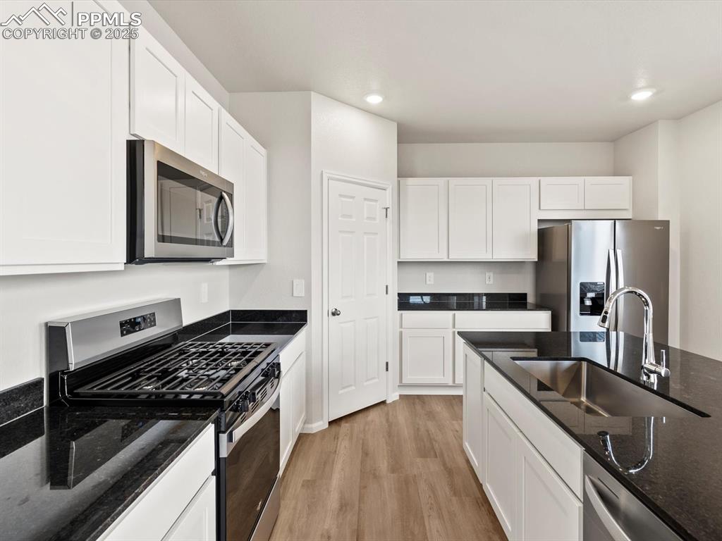 Image 4 of 23: Kitchen with appliances with stainless steel finishes, dark stone counters,
