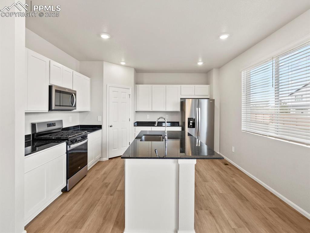 Image 8 of 23: Kitchen with appliances with stainless steel finishes, white cabinets, dark