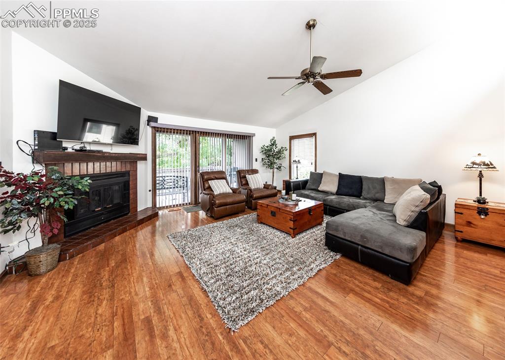 Image 12 of 37: Living area with vaulted ceiling, a ceiling fan, wood finished floors, and 