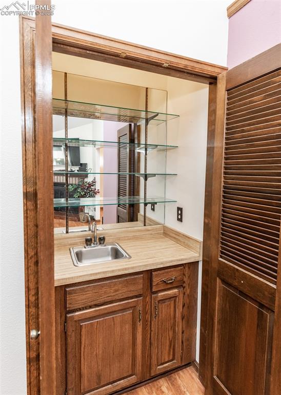 Image 15 of 37: Indoor wet bar featuring light wood-style floors and lighting
