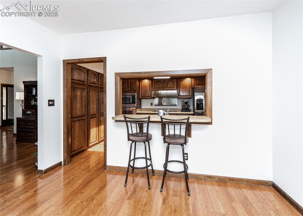 Image 18 of 37: Dining area featuring a breakfast bar, light wood-style floors