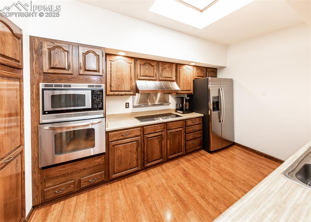 Image 20 of 37: Kitchen with appliances with stainless steel finishes, light countertops, l