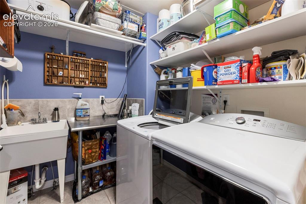 Image 11 of 28: Utility room featuring a built-in sink, tiled backsplash, wall-mounted shel